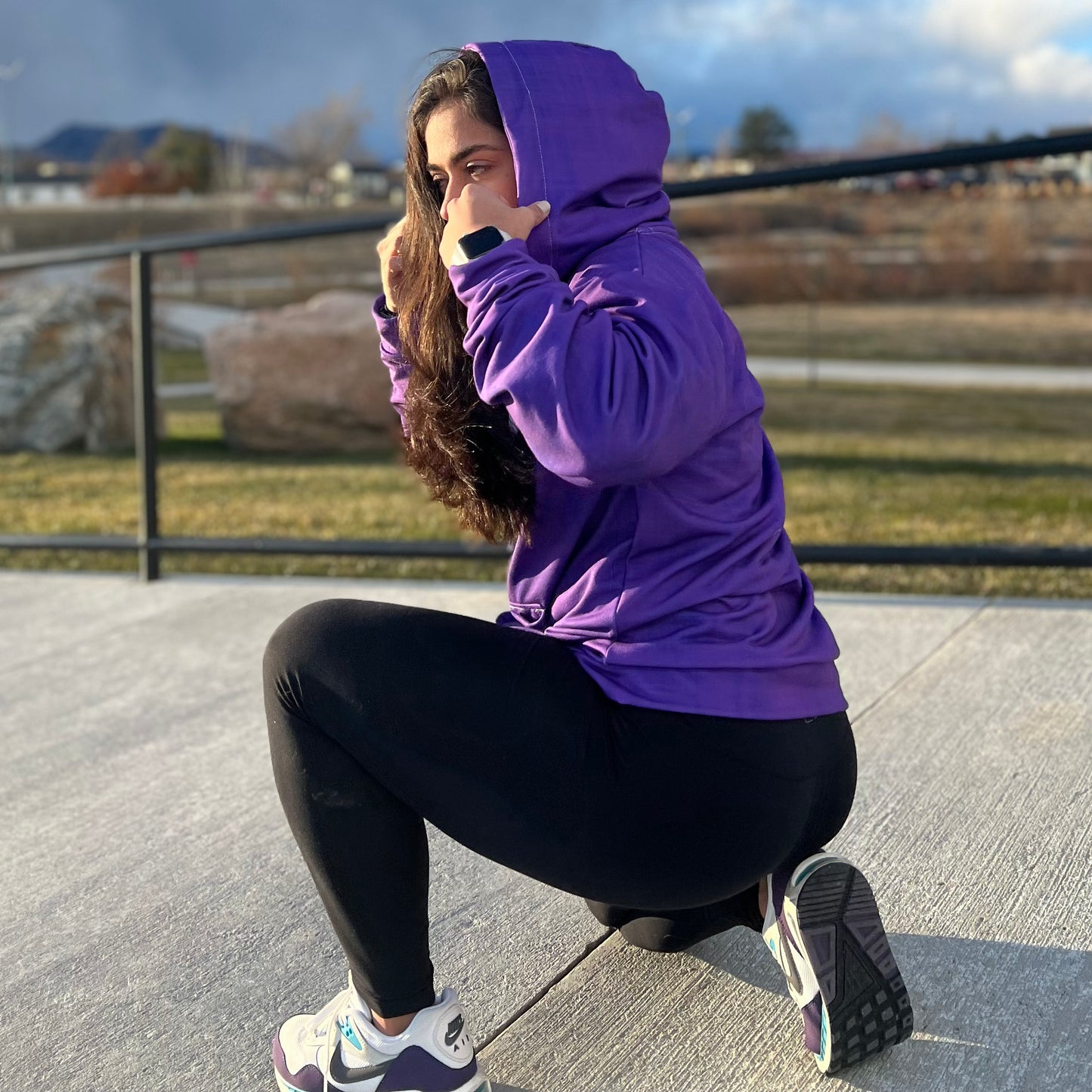 Woman working out and wearing a purple pop zip hoodie.